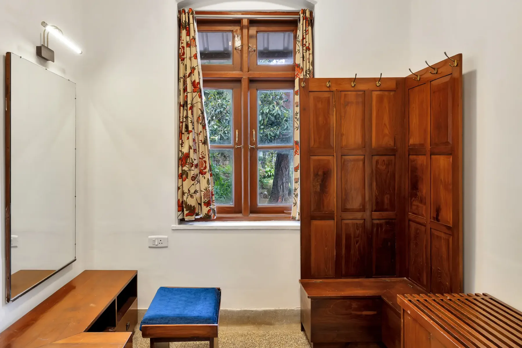 Un área de vestidor en un dormitorio con un armario de madera y una ventana.