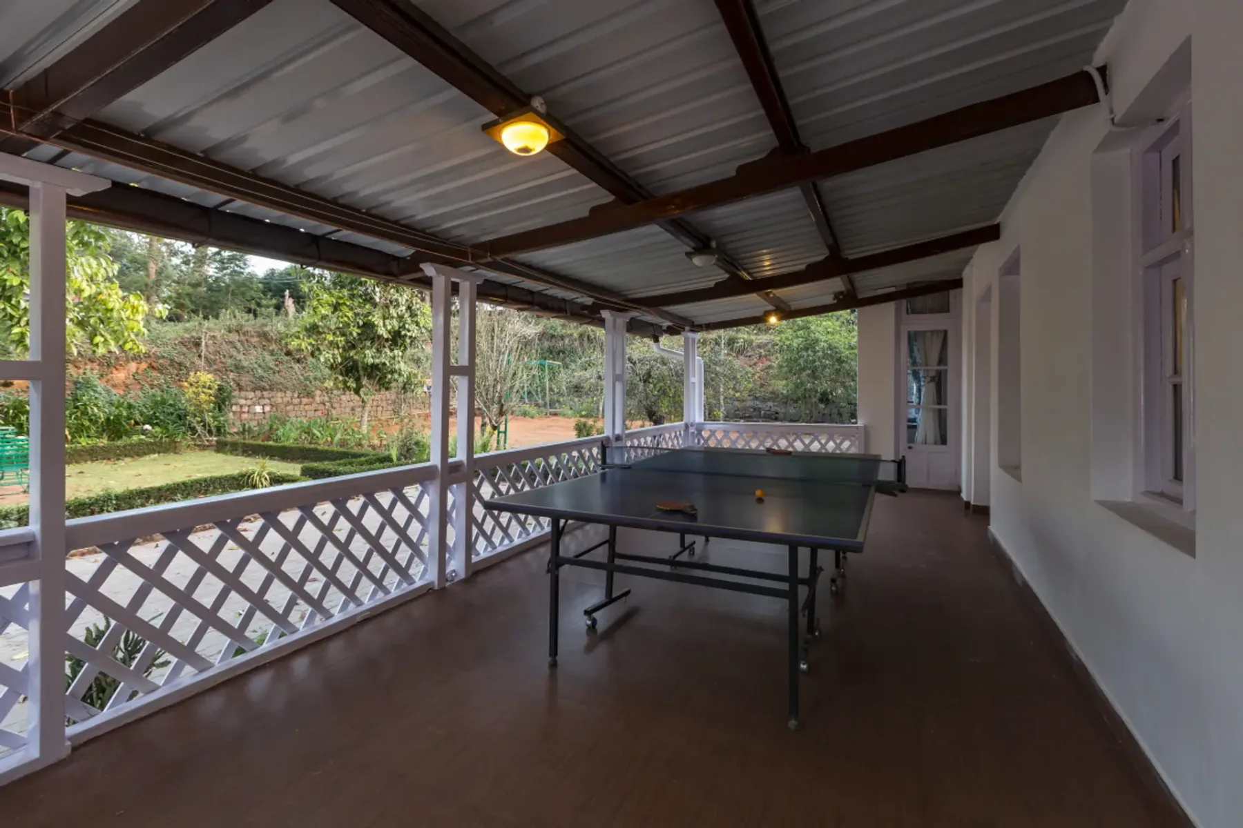 Un patio cubierto con una mesa de ping-pong y vistas al jardín.