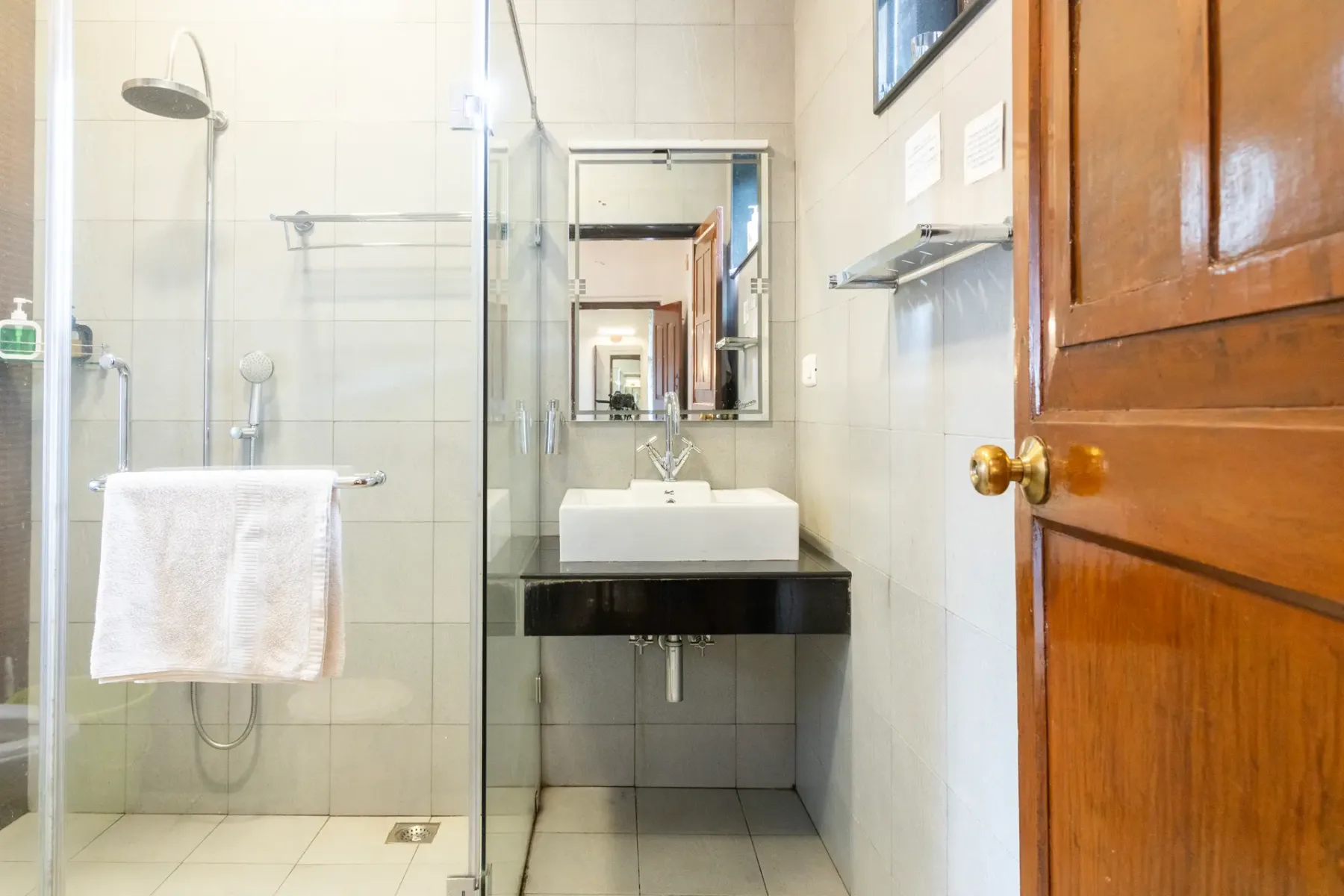 Un baño alicatado con una ducha de vidrio y un lavabo bajo un espejo.