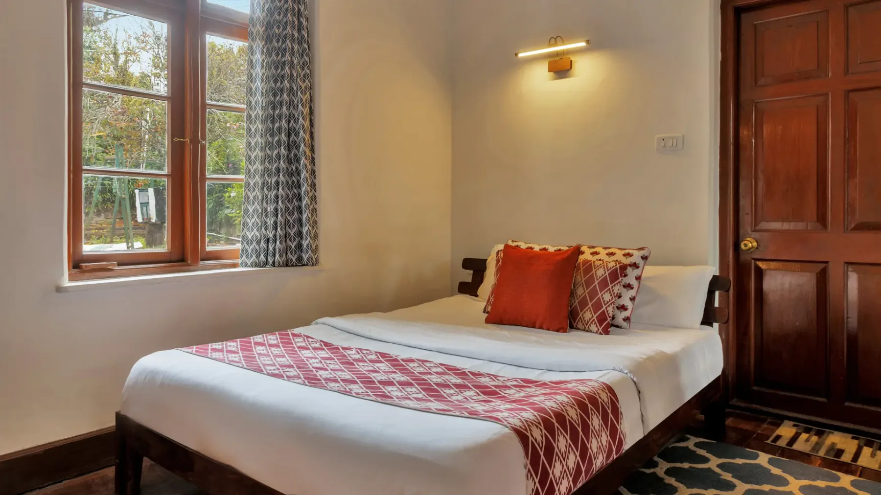 Un dormitorio con una cama bien tendida y una ventana con vista a los árboles.