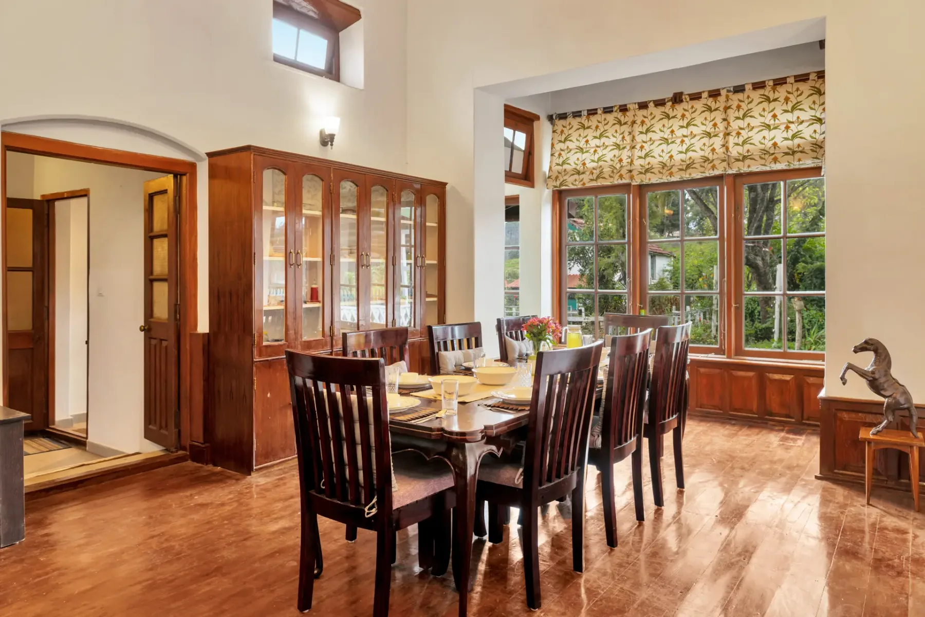 Un comedor con una mesa larga de madera y ventanas grandes.