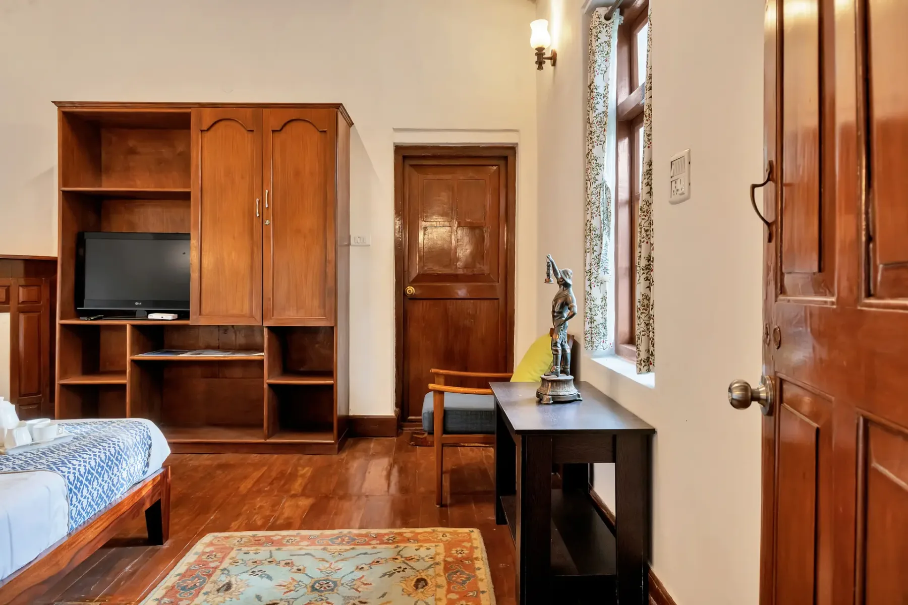 Un dormitorio con muebles de madera, un televisor, una cama y una mesa pequeña.