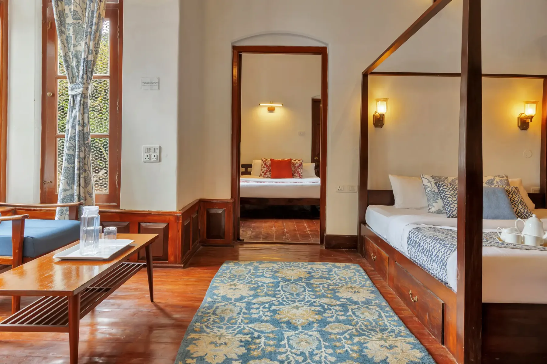 Un dormitorio con dos camas, una alfombra estampada y una ventana con cortinas.