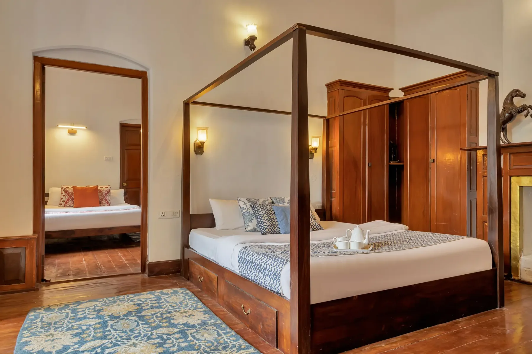 Un dormitorio con una cama con dosel de madera y una alfombra estampada.