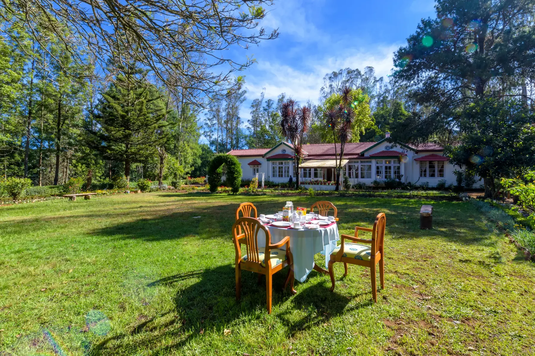 Comedor en el jardín con una mesa puesta y una casa al fondo.