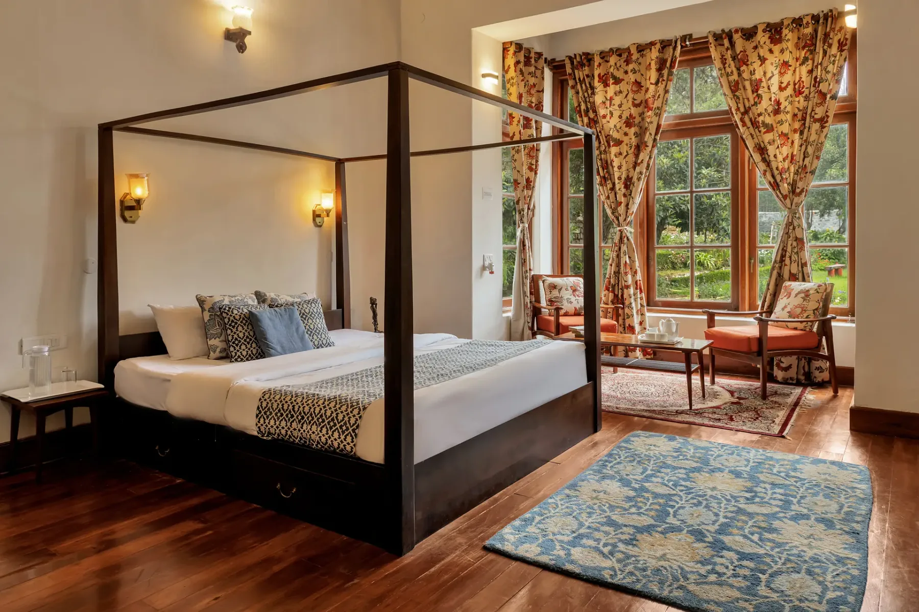 Un dormitorio con una cama con dosel y asientos junto a una ventana grande.