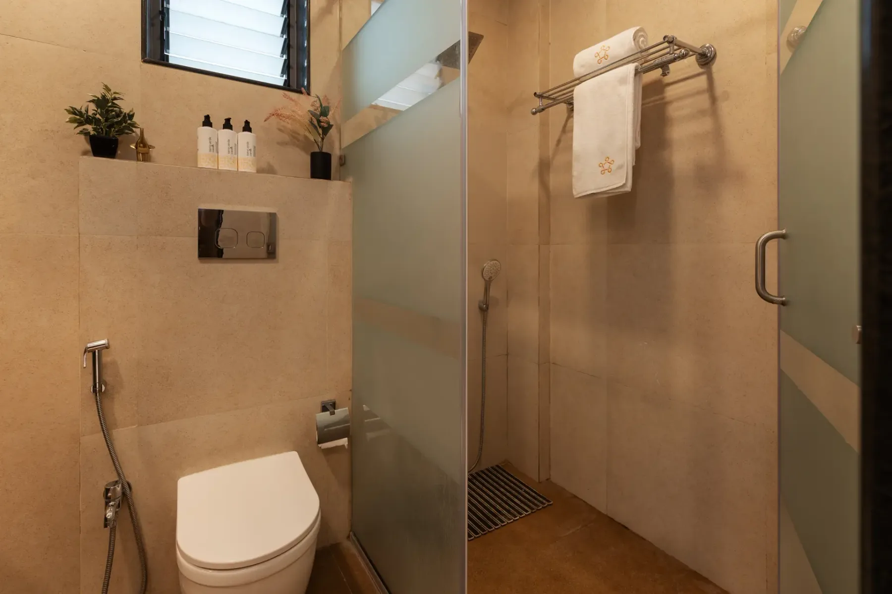 A tiled bathroom with a toilet and a glass shower.