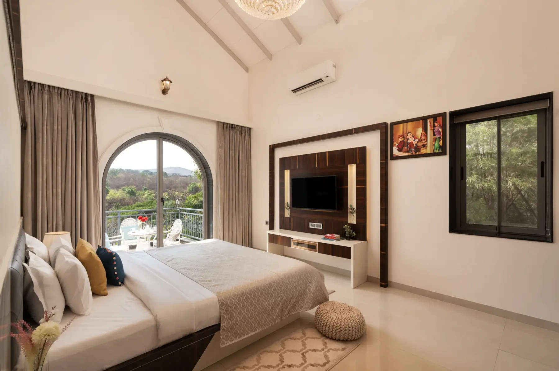 A bedroom with a large bed, television, and arched glass doors opening onto a balcony.