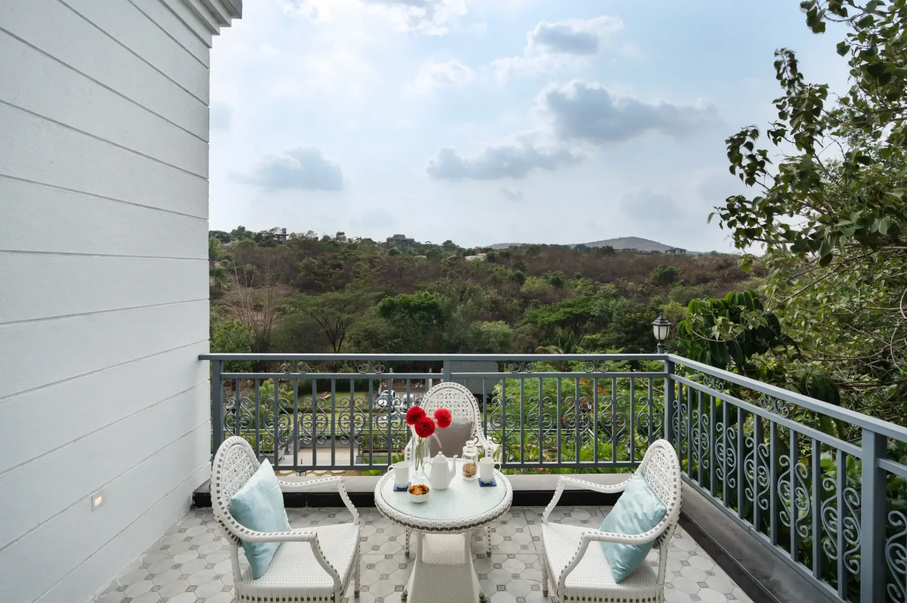 A balcony seating area overlooks green hills, with a small table between two chairs.