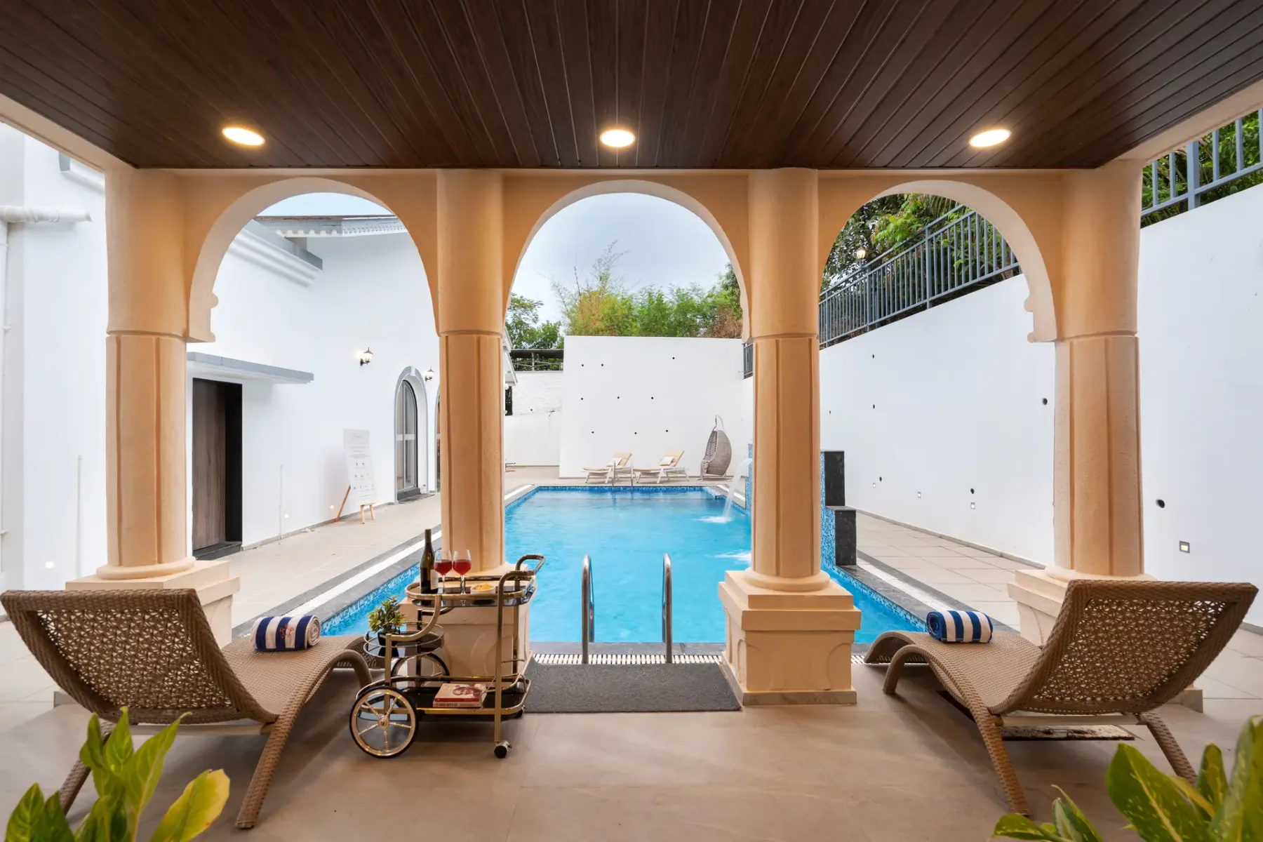 A covered poolside seating area opens onto a blue swimming pool.