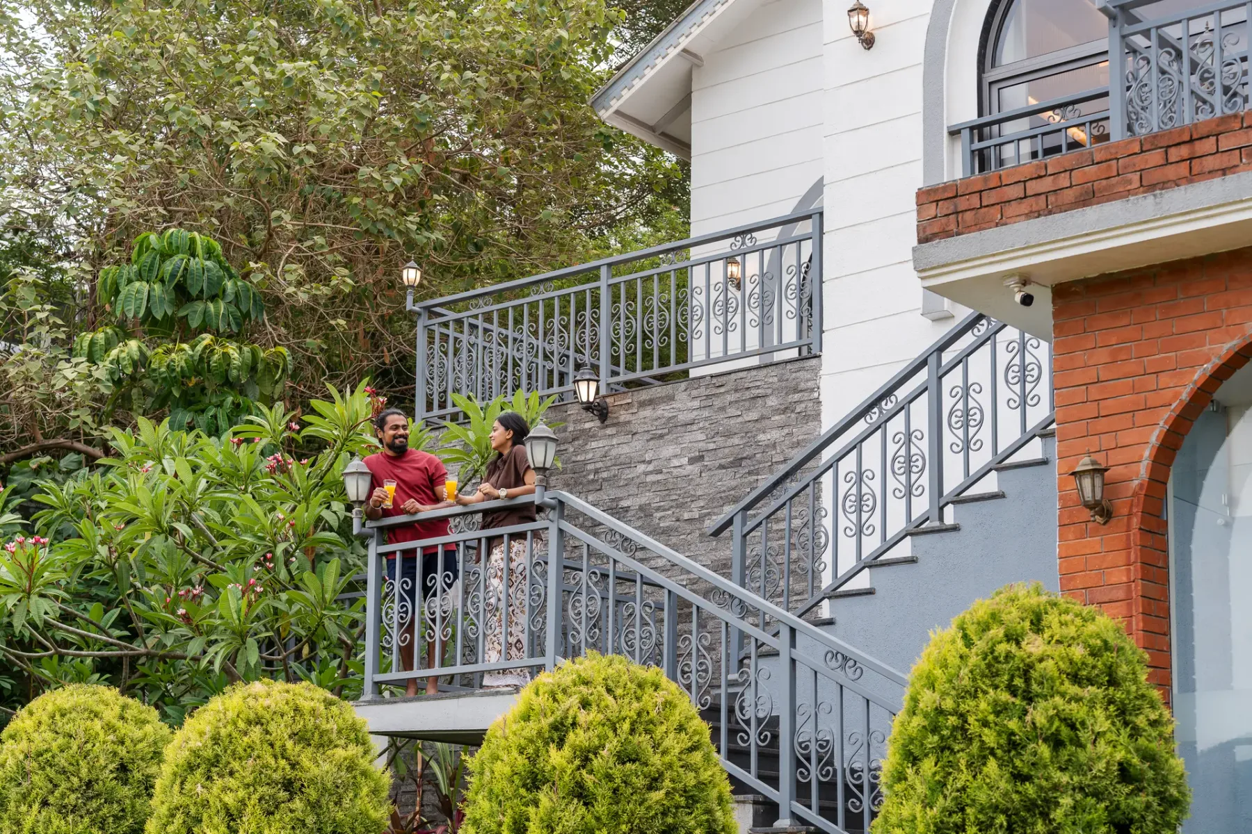 An outdoor staircase and balcony bordered by decorative railings and greenery.