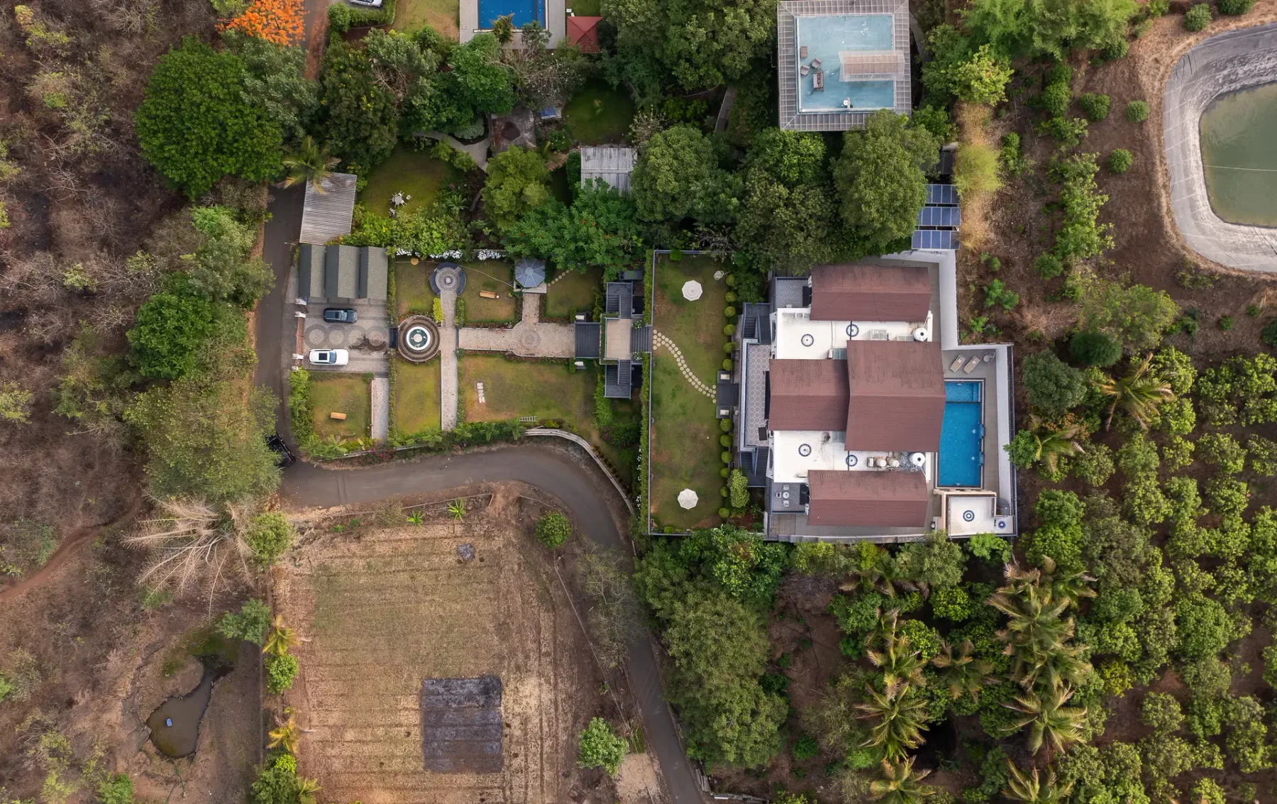 An aerial view shows a house, swimming pool, and landscaped grounds among trees.