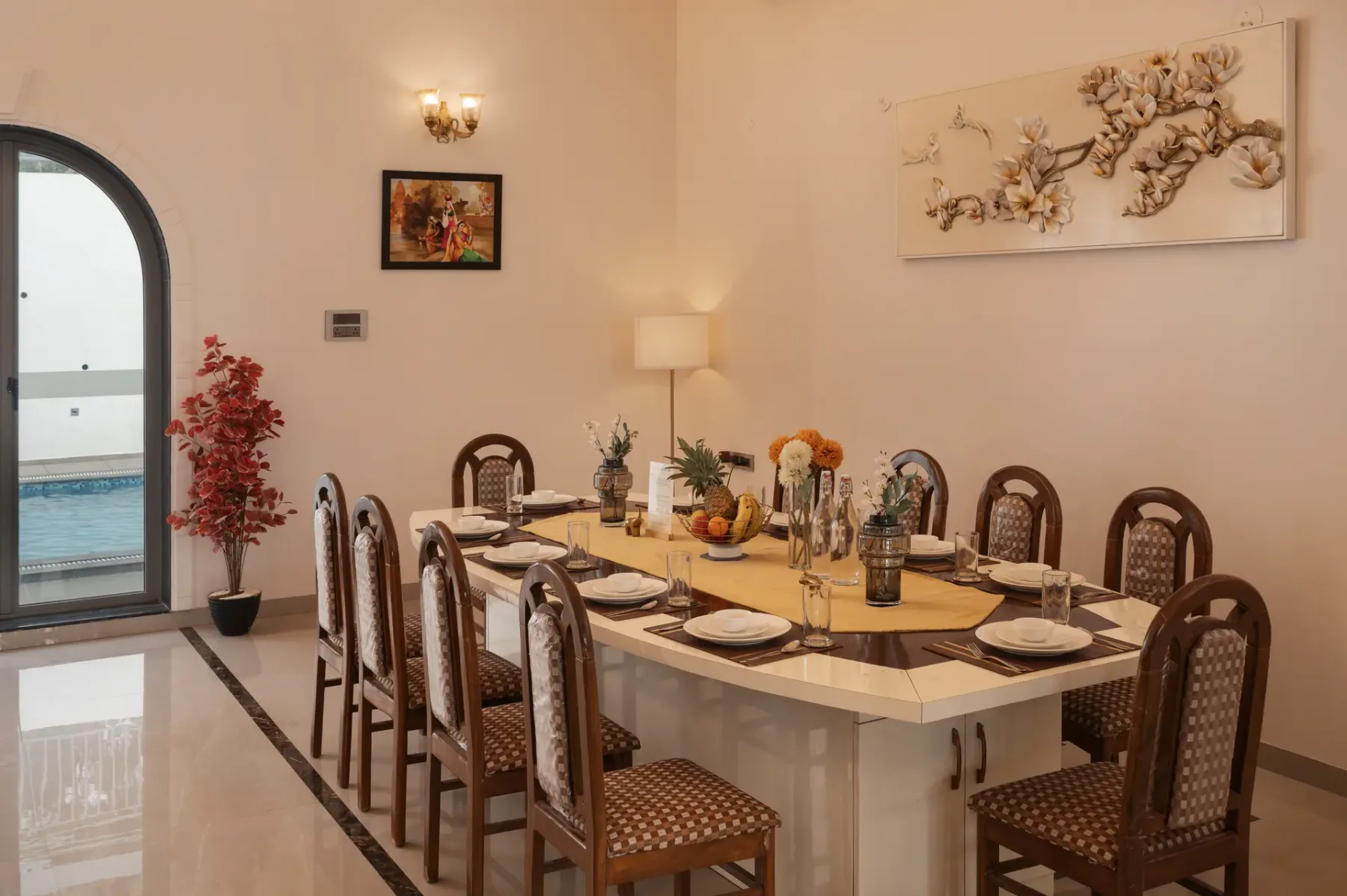 A dining room with a long table set with dishes and surrounded by chairs.