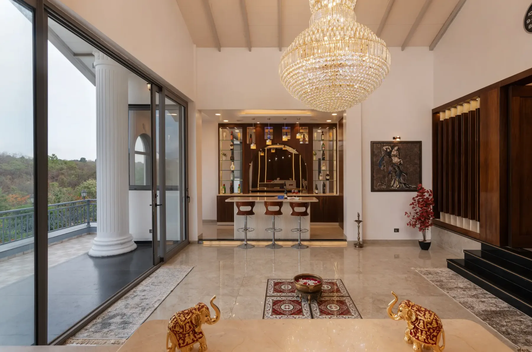 A spacious interior with a chandelier, bar seating, and sliding glass doors.