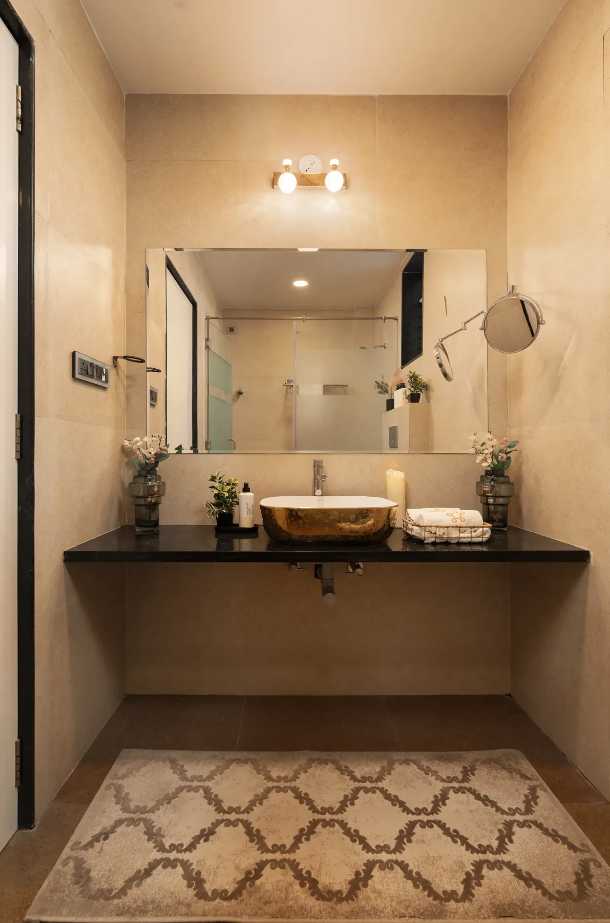 A bathroom vanity with a wide mirror and patterned rug.