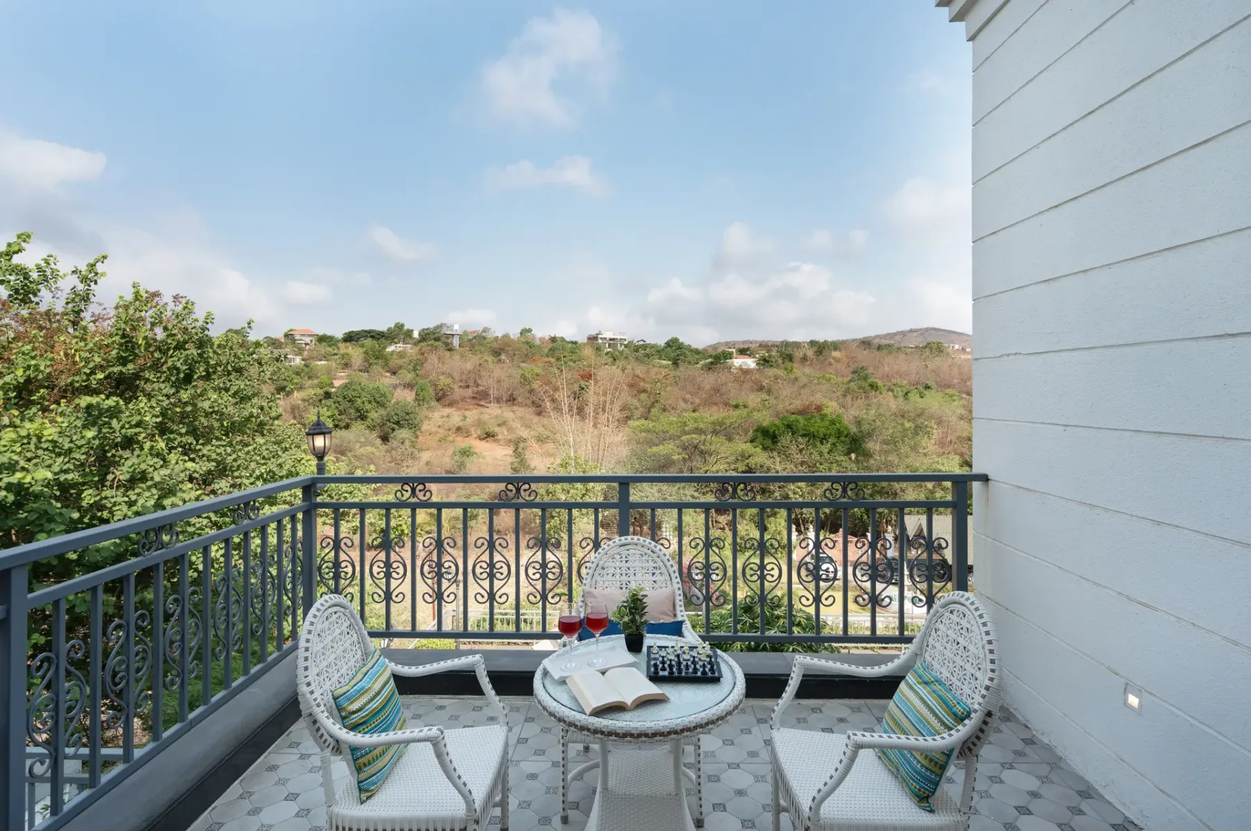A balcony seating area overlooks a green, open landscape.