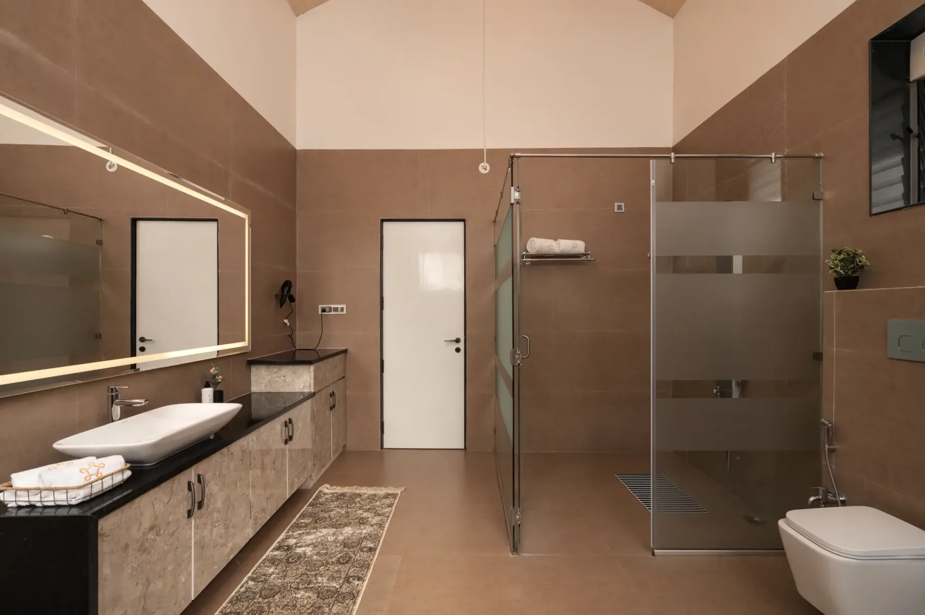 A bathroom with a glass shower, vanity, and toilet.