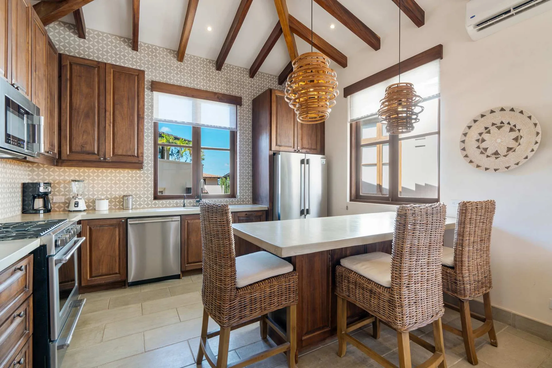 A kitchen and dining area with a large island and woven seating.