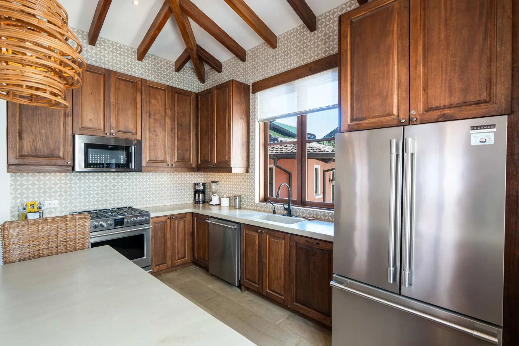 A kitchen with wooden cabinets, stainless steel appliances, and a broad countertop.