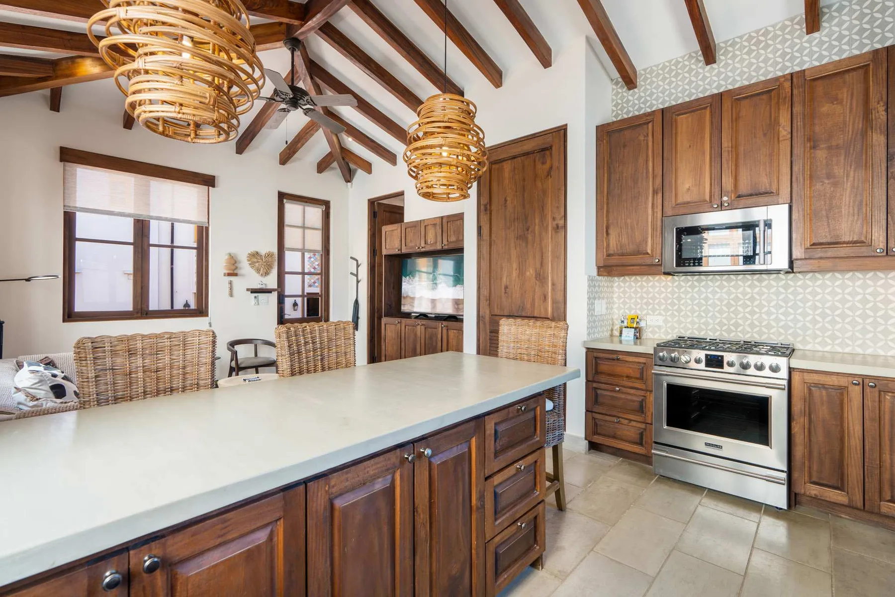 A spacious kitchen with wooden cabinets, a large island, and exposed ceiling beams.