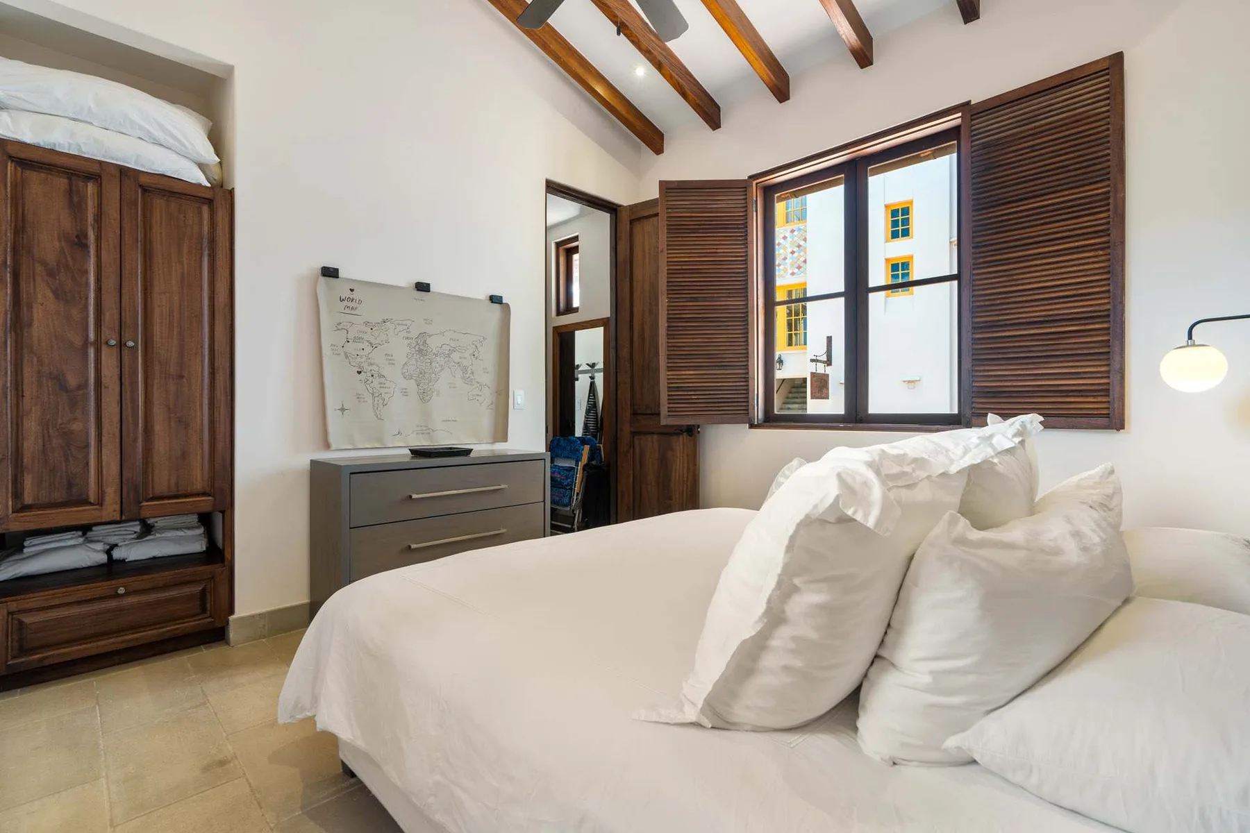 A bedroom with a large bed and a window with wooden shutters.