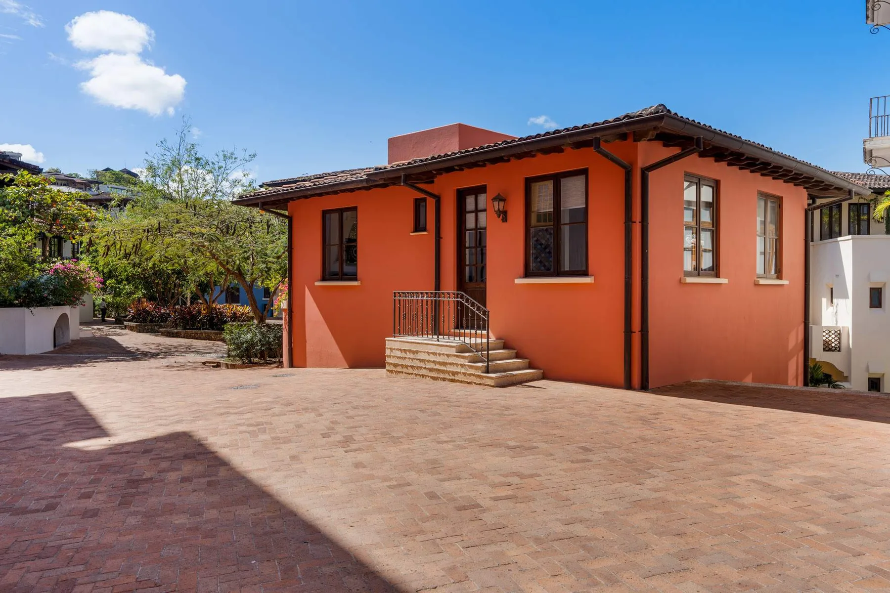 An orange house opens onto a broad paved courtyard.