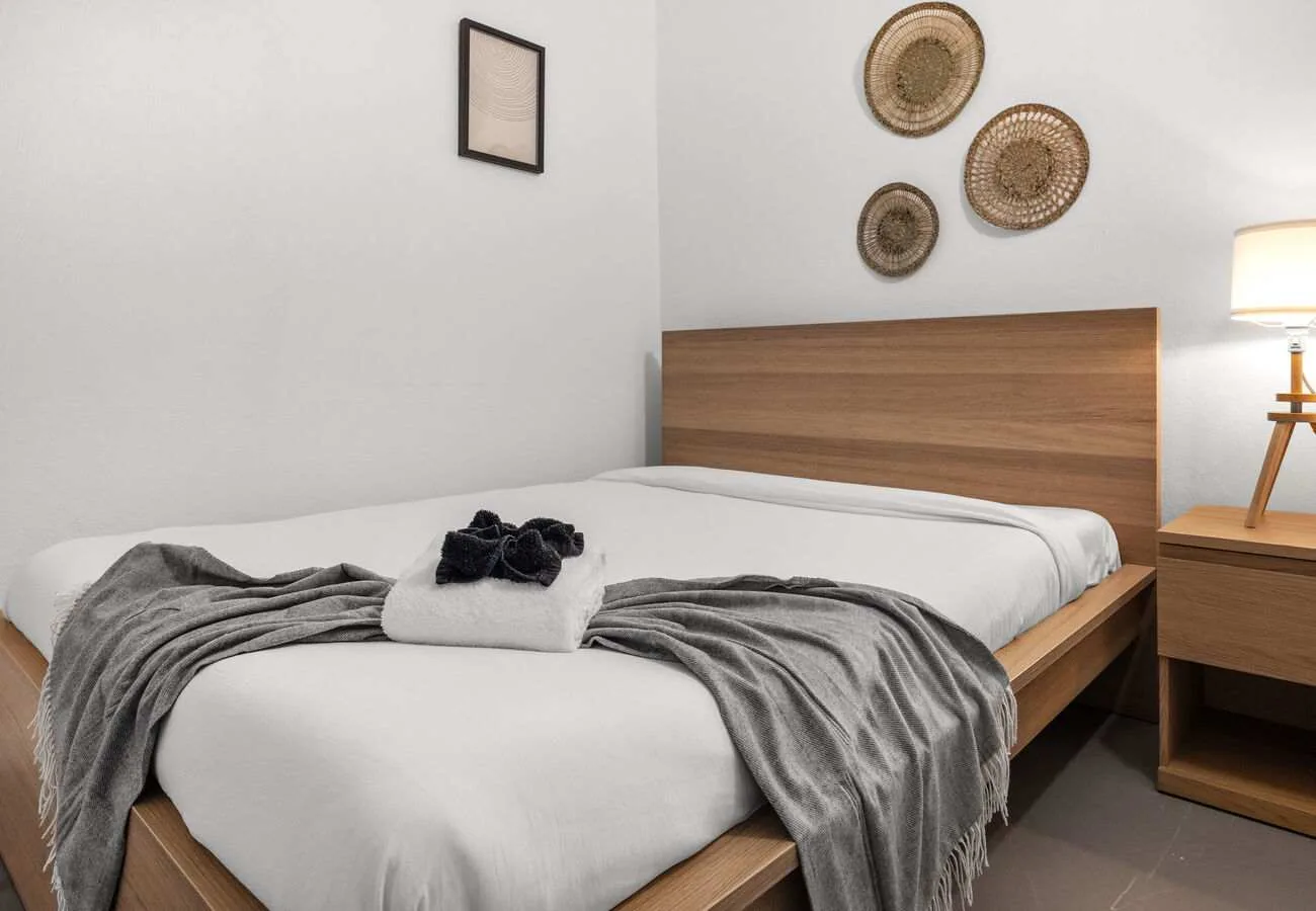 A neatly made bedroom with a wooden headboard and gray bedding.
