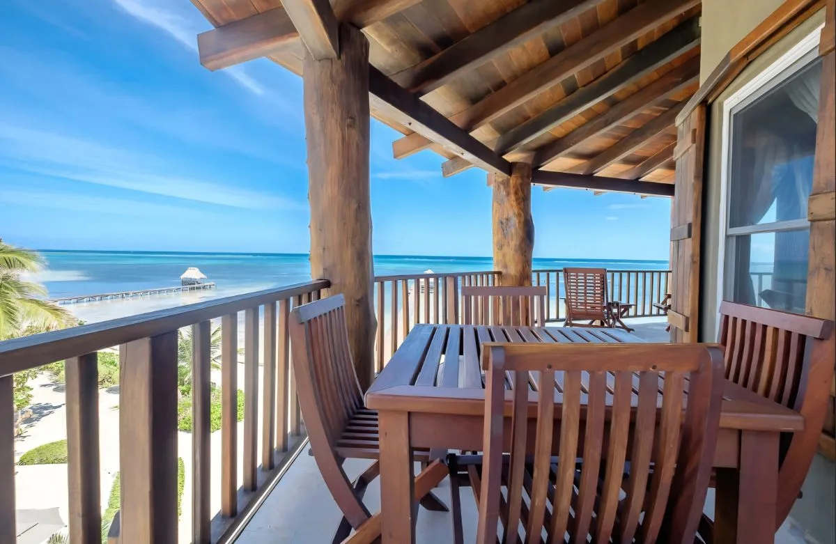 Una terraza cubierta con muebles de comedor al aire libre da al océano.
