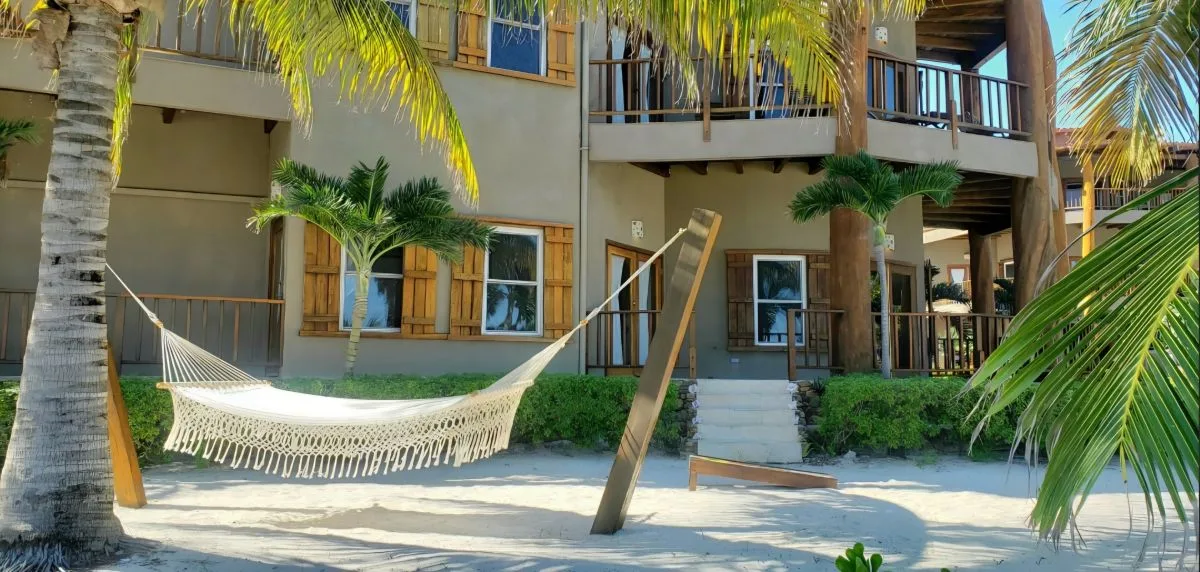 Zona común: Una hamaca cuelga en un patio de arena junto a un edificio con balcones.