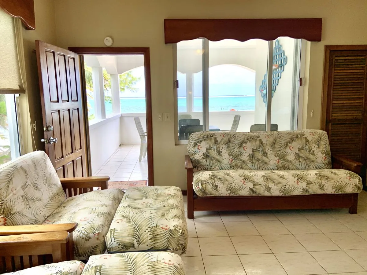 Una sala de estar con asientos estampados y vista al mar a través de las ventanas.