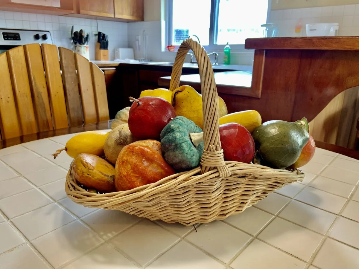 Una cocina con una cesta de frutas de colores sobre la encimera.