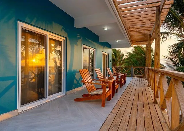 A covered outdoor deck with wooden seating beside a blue wall.