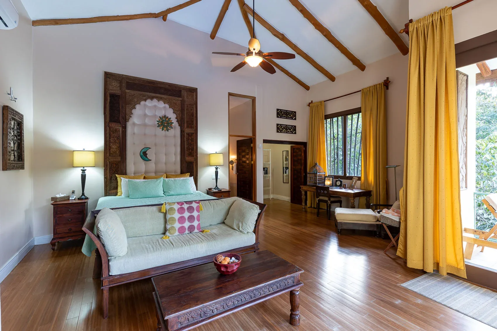 Un dormitorio amplio con una cama, asientos y vigas de madera a la vista.