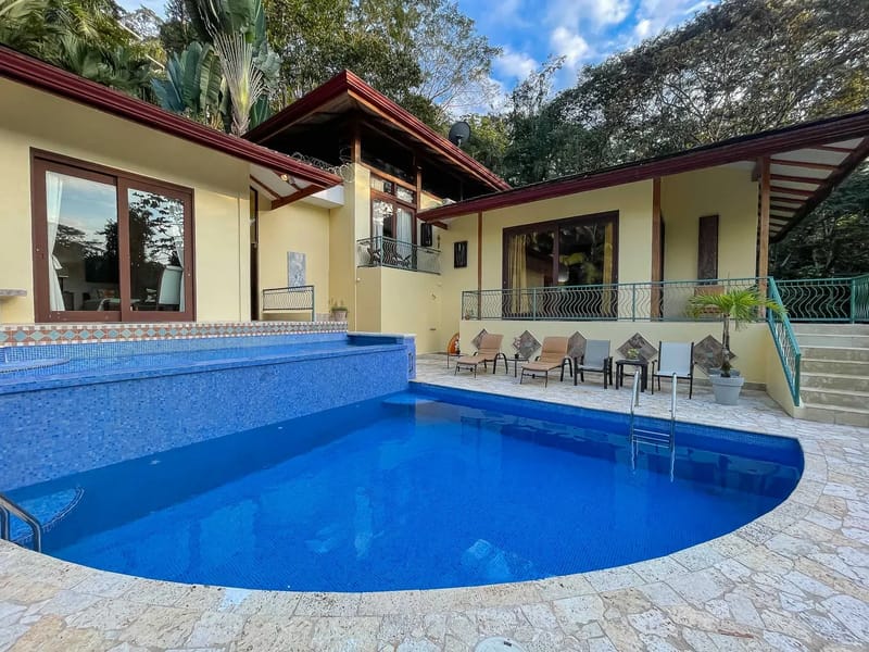 Villa Michelina · 25. The outdoor space features a large blue tiled pool and an adjacent lounging area with tropical views, offering an inviting setting for relaxation beside the multi-level villa.