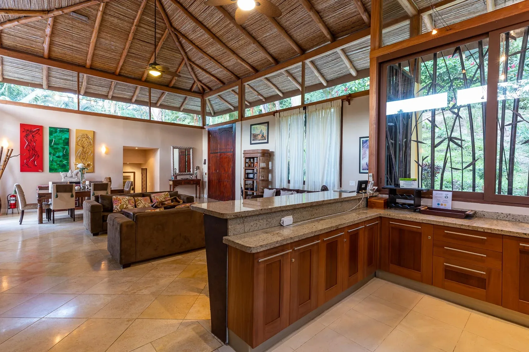 Una sala de estar y cocina de planta abierta con techo alto y ventanas amplias.
