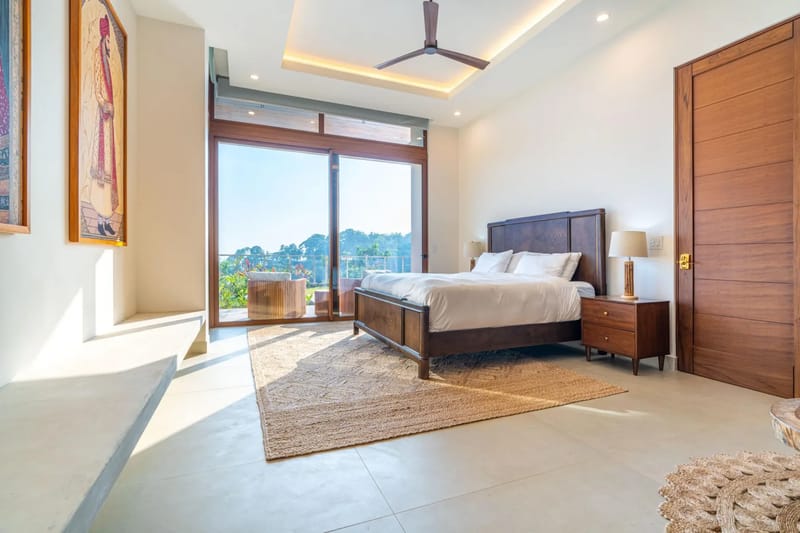 Casa Bella Vina · 12. Este dormitorio cuenta con una cama king, mobiliario de madera de tonos intensos y puertas de vidrio de piso a techo que dejan entrar abundante luz natural y ofrecen vistas a la selva.