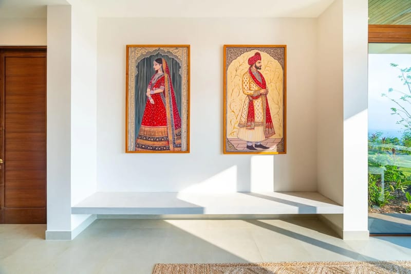 Casa Bella Vina · 16. Un luminoso vestíbulo, con obras de arte de inspiración balinesa y un banco bajo, ofrece vistas a la vegetación tropical y al océano a lo lejos a través de un gran panel de vidrio, complementado por una puerta de madera de tonos cálidos.
