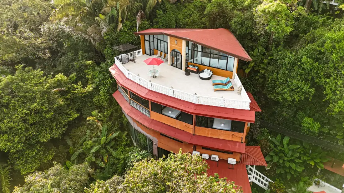 A multi-level house with a broad terrace surrounded by dense greenery.