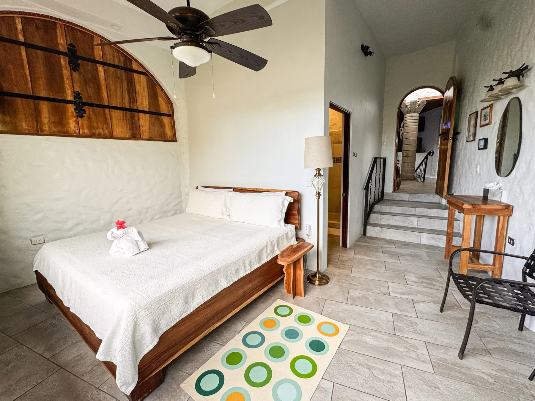 A bedroom with a wooden bed and a tiled passage leading to a raised landing.