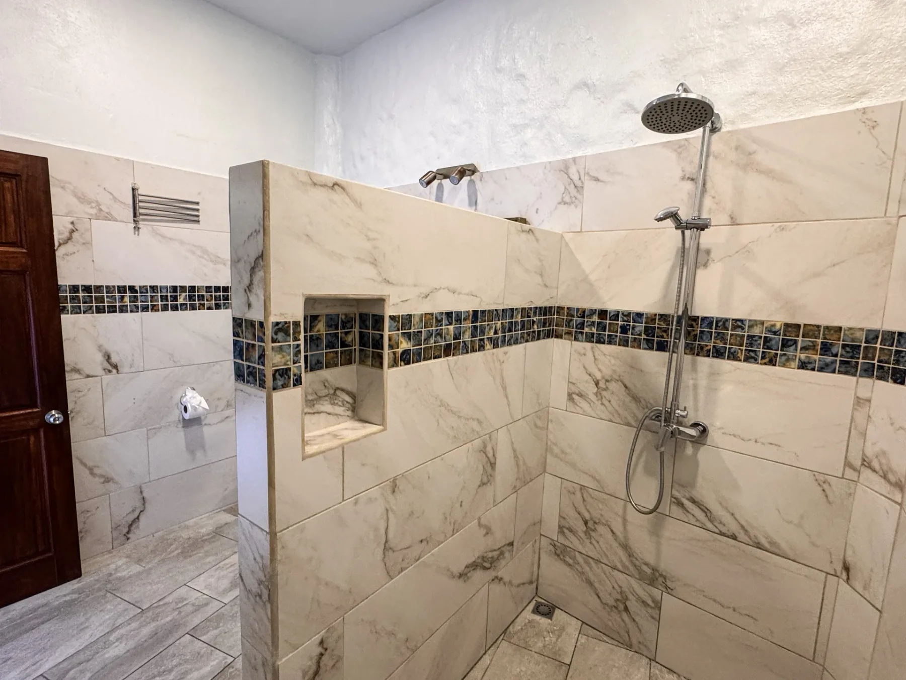 A tiled bathroom with a walk-in shower and a recessed wall niche.