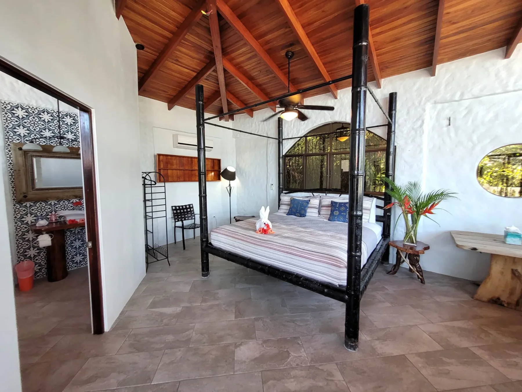 A bedroom with a four-poster bed beneath a wooden vaulted ceiling.