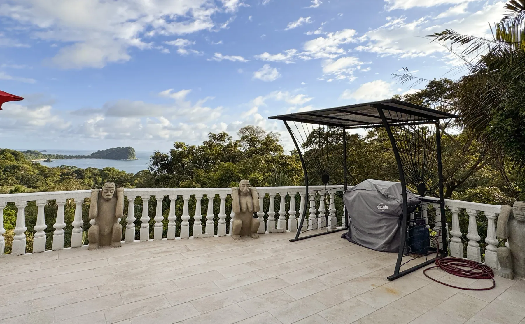 A paved outdoor terrace overlooks a green landscape and water.