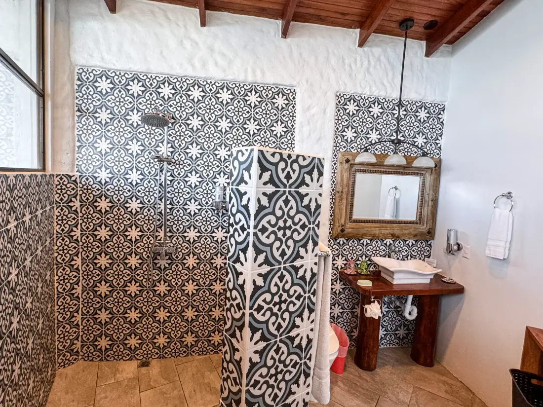 A tiled bathroom with a shower area and a wooden sink vanity.