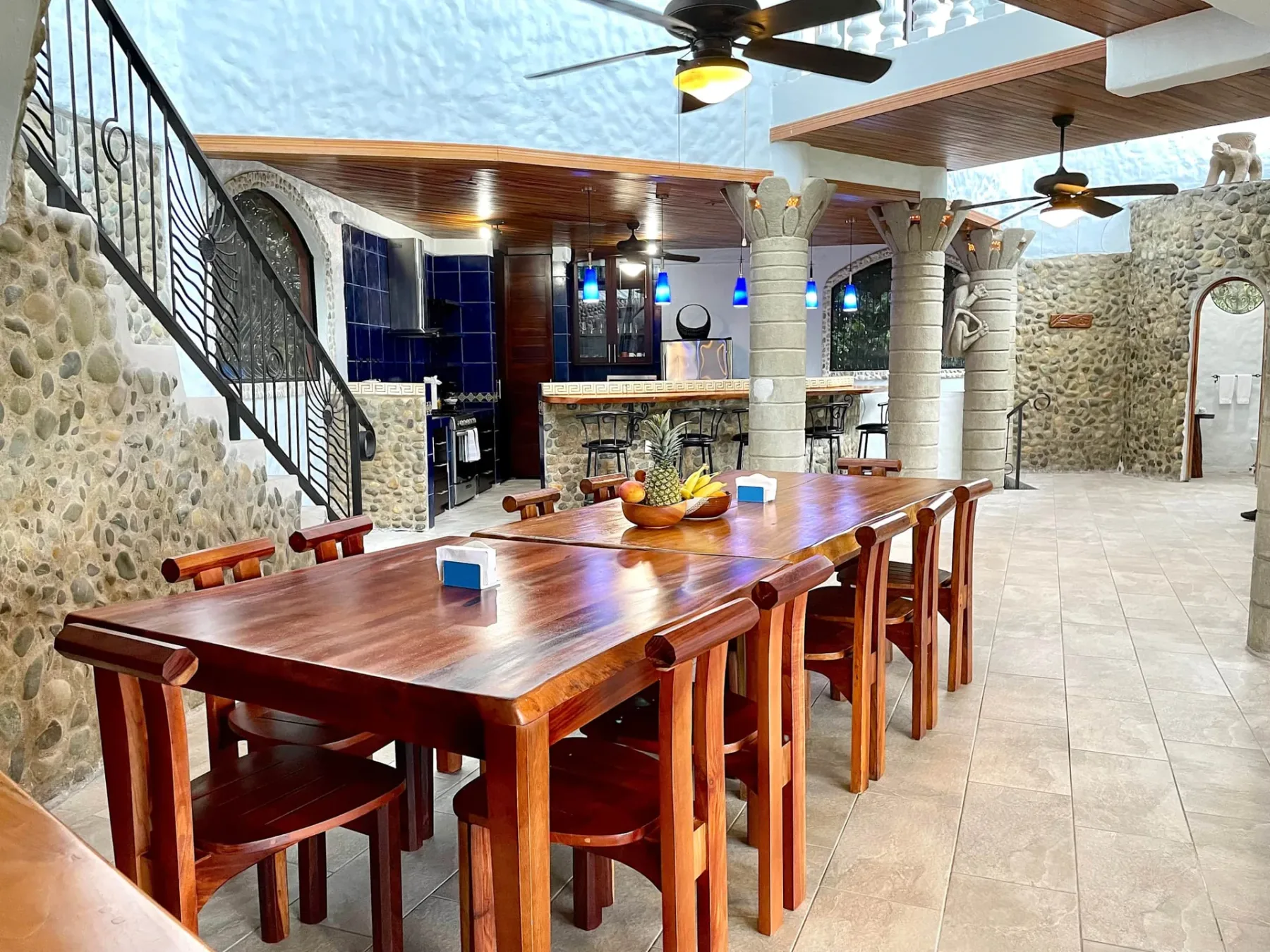 A dining area with a long wooden table and seating beneath ceiling fans.