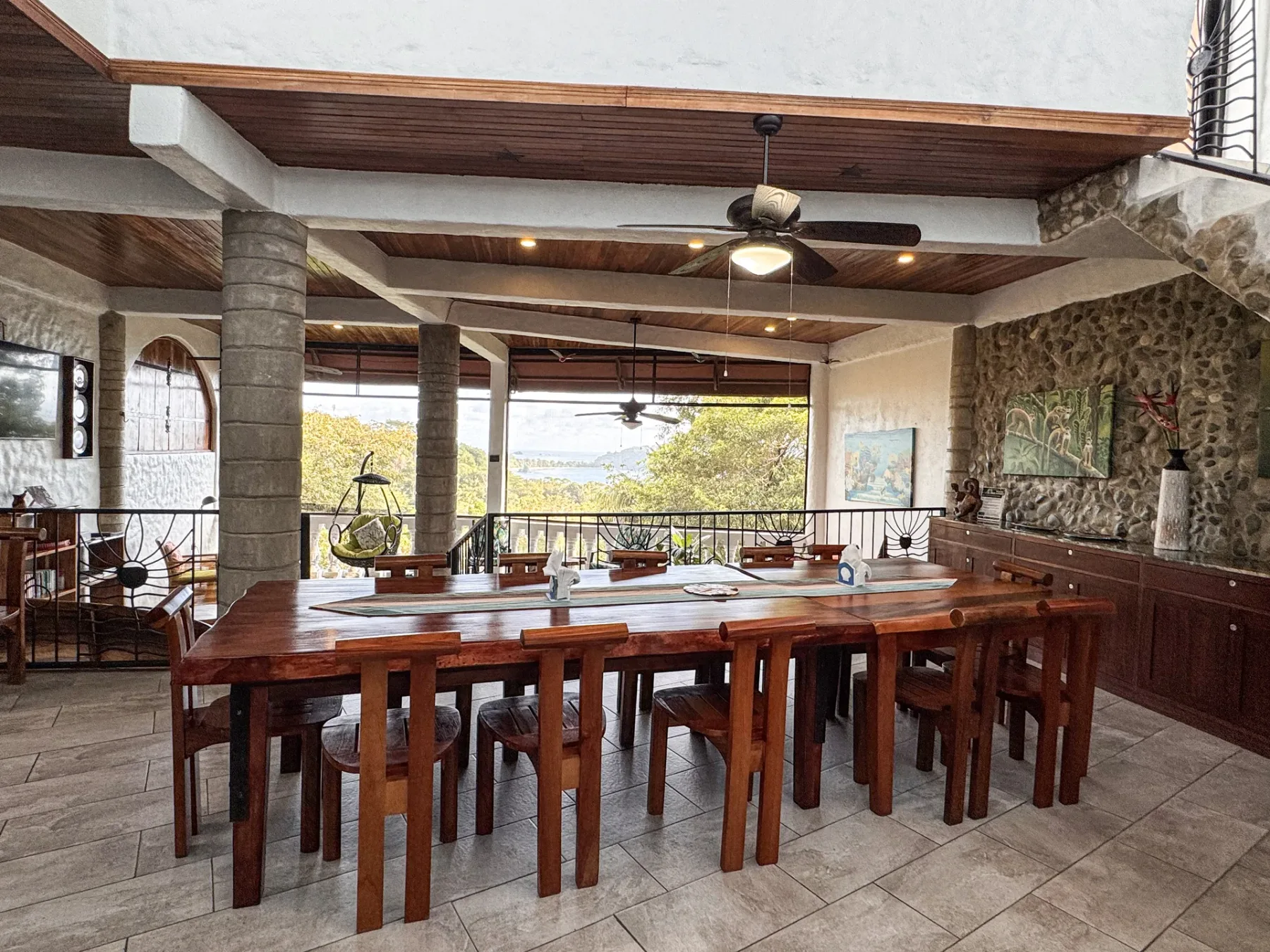 A spacious dining area with long wooden tables and chairs beside large windows.