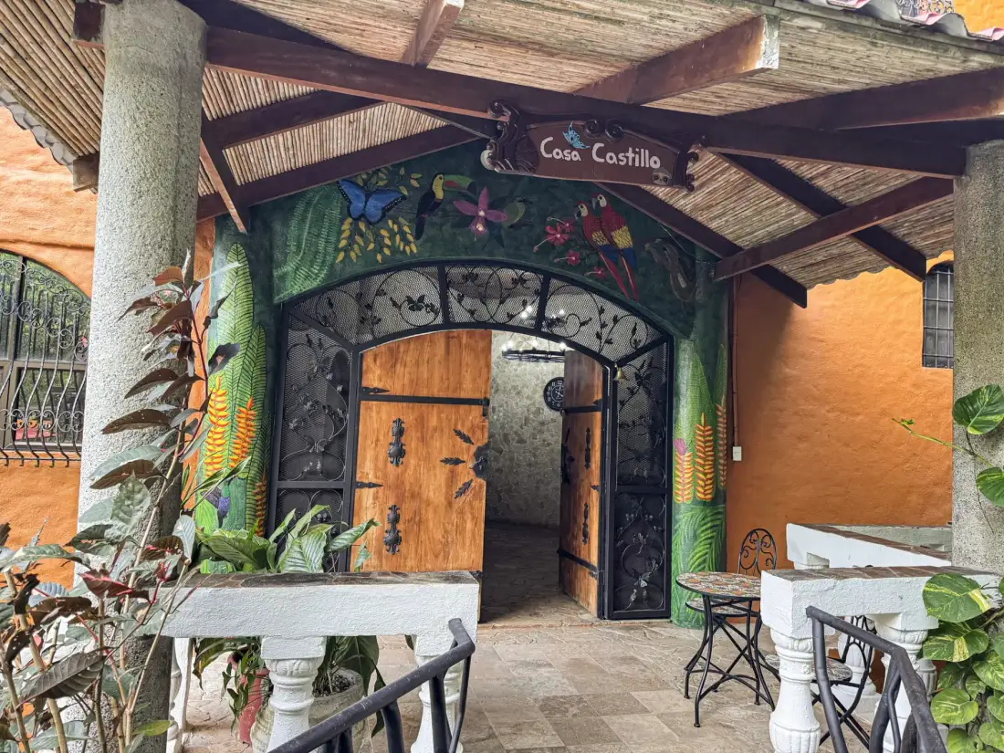 An entrance with painted tropical murals surrounds an open wooden doorway beneath a covered roof.