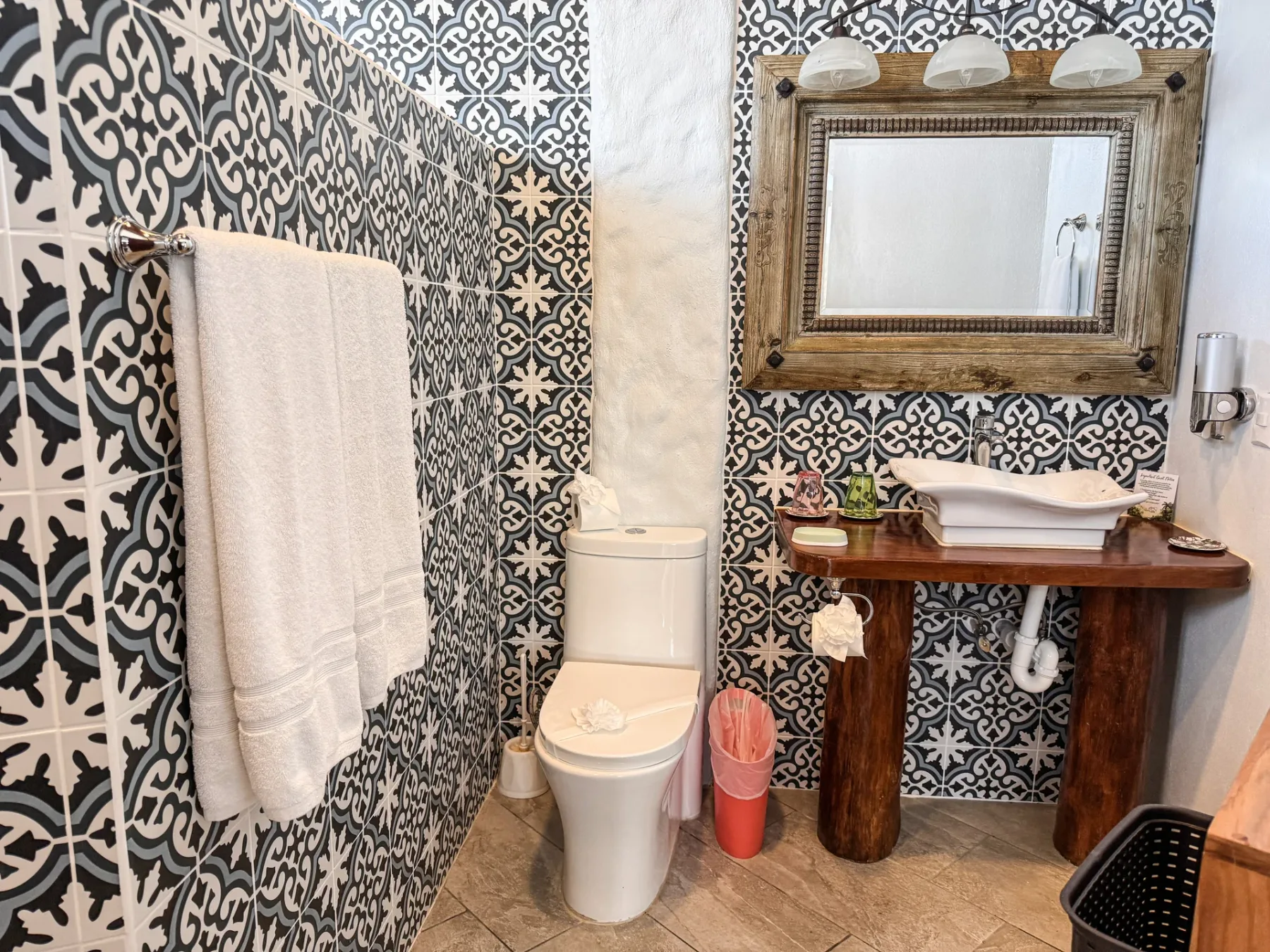 A bathroom with a toilet, a sink, and patterned wall tiles.