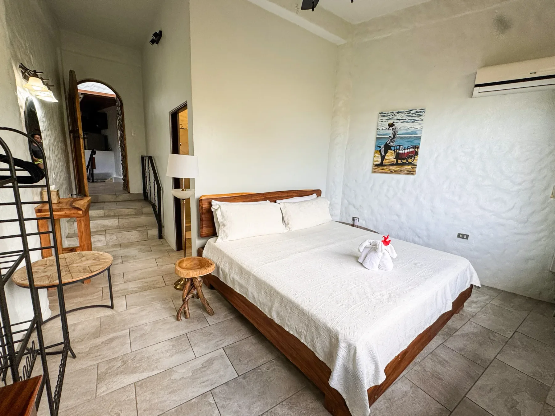 A bedroom with a double bed, a wall-mounted air conditioner, and tiled flooring.