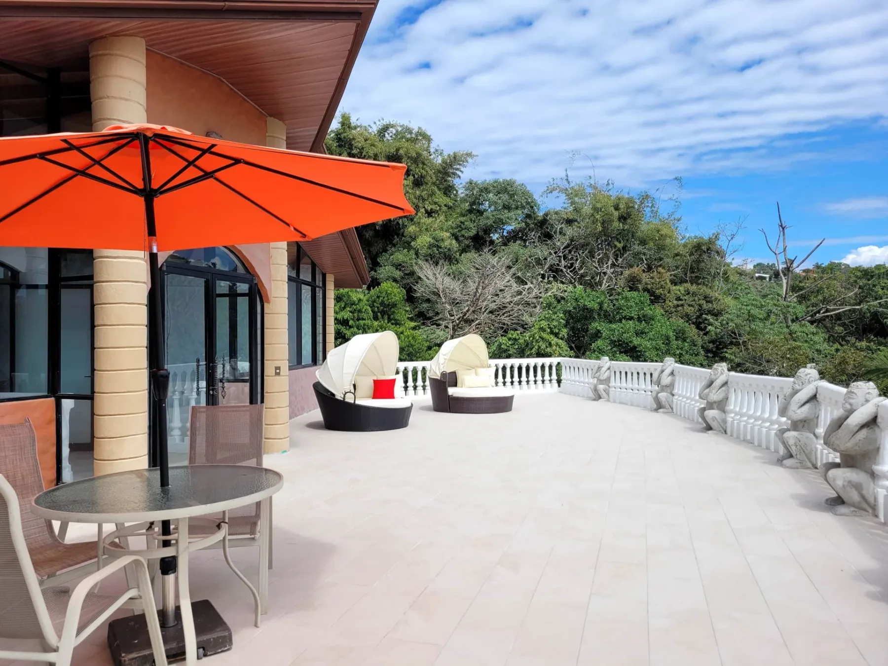 A spacious outdoor terrace with an orange umbrella and outdoor seating.