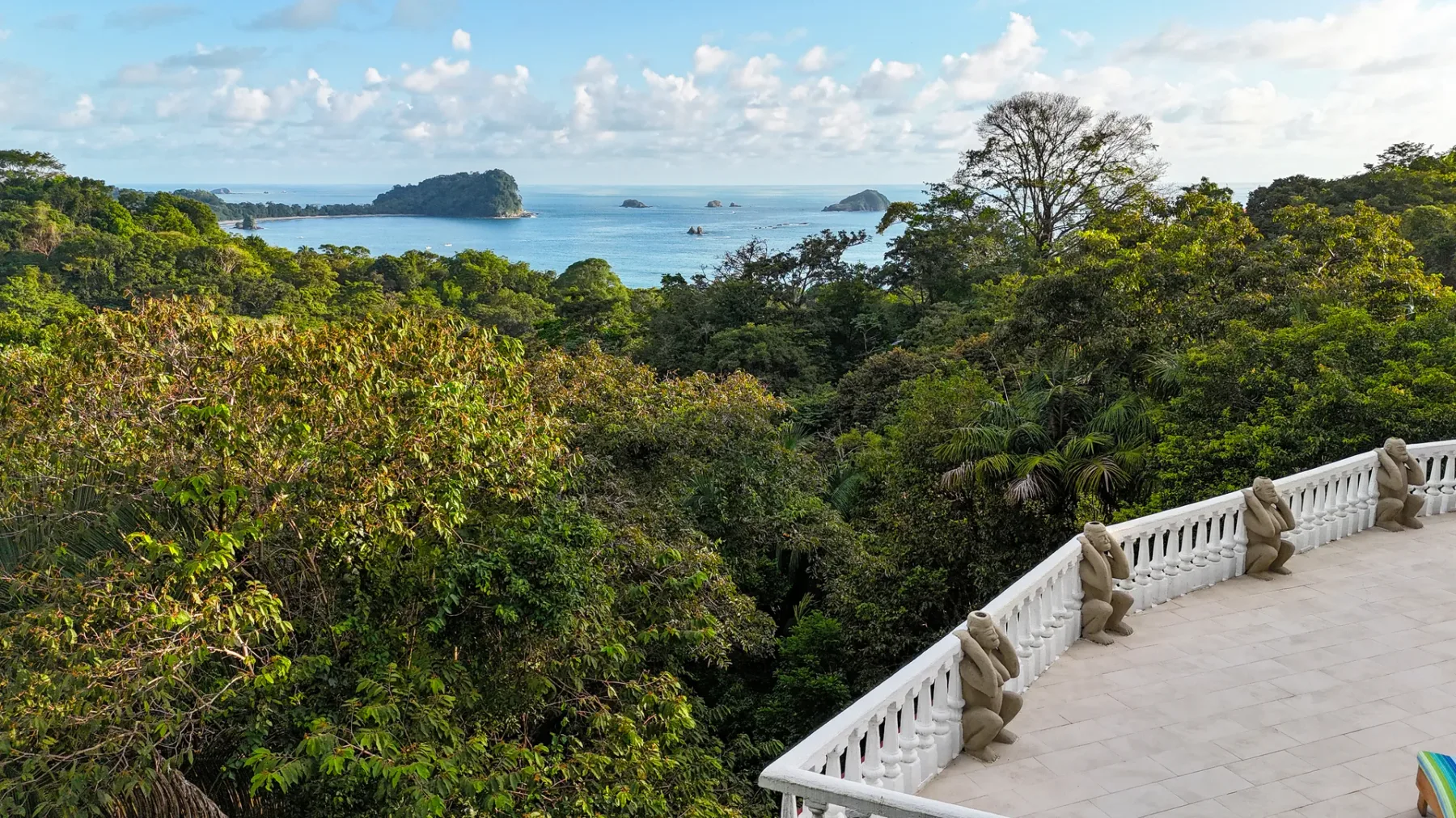 A terrace overlooks a tree-covered coastline and blue water.